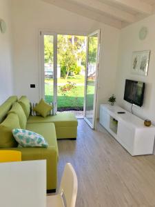 a living room with a green couch and a tv at Il Miraggio in Fregene