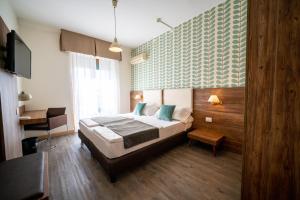 a bedroom with a bed and a desk and a tv at B City Hotel in Bardolino