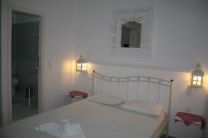 1 cama blanca con 2 almohadas y espejo en Olympias Studio "Pitsidia", en Pitsidia