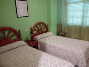 two beds in a bedroom with green walls at Hostal O Pincho in Ponte Do Porto