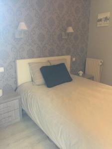 ein Schlafzimmer mit einem großen weißen Bett mit einem blauen Kissen in der Unterkunft Hotel Chaplin in Blankenberge