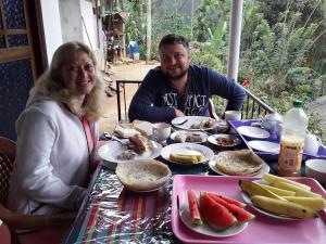 a man and a woman sitting at a table with food at Nine Arch Araliya Homestay in Ella