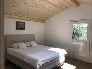 1 dormitorio con cama blanca y ventana en Jade B&B en Bouveret