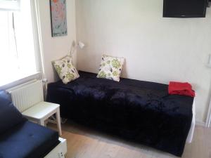 um quarto com uma cama preta e uma cadeira em Lilleledgaard Apartment em Ringkøbing