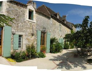 Saint-Antoine-de-BreuilhにあるChambres d'Hôtes La Bastide des Trémièresの通りに緑の艶戸のある古い石造りの家