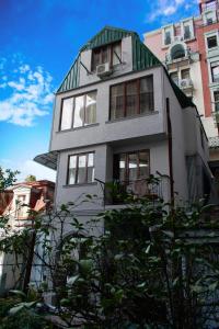 ein großes weißes Haus mit grünem Dach in der Unterkunft Guest House Yana in Batumi