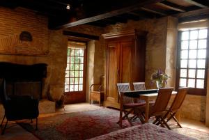 a dining room with a table and chairs and windows at Chambres d'Hôtes La Bastide des Trémières in Saint-Antoine-de-Breuilh