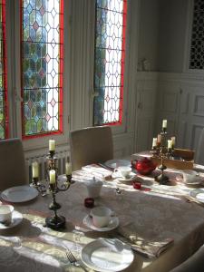 une salle à manger avec une table, des chaises et des vitraux dans l'établissement Château de Launay, à Méry-Corbon