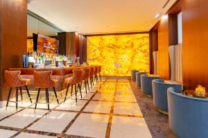 a restaurant with a bar with chairs and a yellow wall at TURIM Boulevard Hotel in Lisbon