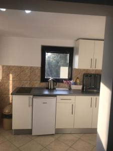 a kitchen with white cabinets and a sink and a window at Apartman Veronika in Starigrad-Paklenica