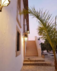 a stairway leading up to a building with a palm tree at Hotel de Charme Capela das Artes in Armação de Pêra