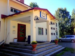 ein weißes Gebäude mit einer roten Tür und einer Treppe in der Unterkunft Vanhan Koulun Majatalo-Old School Guest House in Kolinkylä