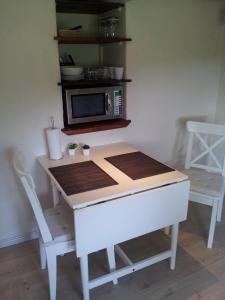 uma cozinha com uma mesa, um micro-ondas e cadeiras em Lilleledgaard Apartment em Ringkøbing
