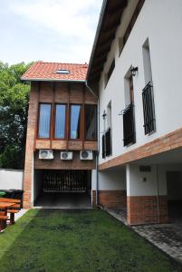 a house with windows and a grass yard at Albatrosz Apartman in Gyula