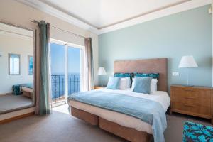a bedroom with a large bed and a large window at Balancal Apartments and Villas Palheiro Village in Funchal +207 photos
