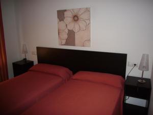 a bedroom with two red beds and a painting on the wall at Gemelos 26 - Fincas Arena in Benidorm +59 photos