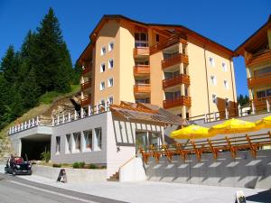 ein Gebäude mit Stühlen und Sonnenschirmen davor in der Unterkunft Hotel-Aparthotel San Bernardino in San Bernardino