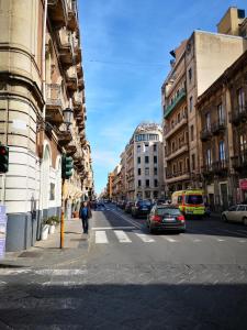 una calle de la ciudad con coches aparcados en la calle en Maison Decò en Catania