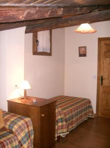 Un dormitorio con 2 camas y una lámpara en un escritorio. en Casa Rural Benito, en Las Cuevas de Cañart