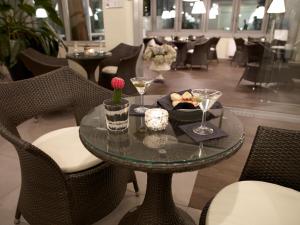 a glass table with chairs and wine glasses on it at Hotel Montini Linate Airport in Peschiera Borromeo