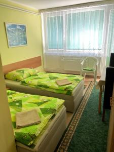 1 dormitorio con 2 camas, mesa y ventana en Galas ubytovani v soukromi, en Brno