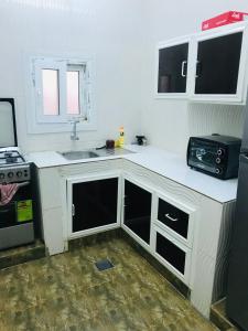 a kitchen with white counters and a sink and a stove at Galaxy VIP in Salalah