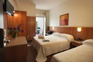 a hotel room with two beds and a television at Hotel Principe di Piemonte in Rimini