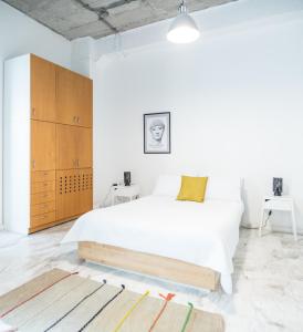 a white bedroom with a large bed and wooden cabinets at Concierge Downtown in Athens