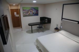 a hotel room with a bed, desk and television at Fórmula Arrey Hotel - Teresina in Teresina
