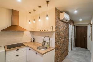 a kitchen with a sink and a brick wall at Amos Apartment in Košice