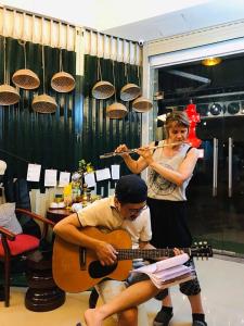 Eine Frau, die neben einem Mann steht und Gitarre spielt. in der Unterkunft BAP.Homestay in Ho-Chi-Minh-Stadt