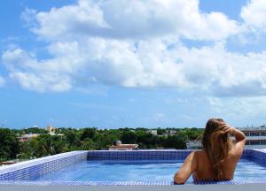 uma mulher sentada à beira de uma piscina em Hotel Pal Cozumel em Cozumel