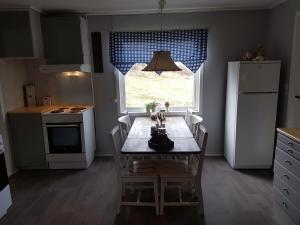 a kitchen with a table with chairs and a window at Leite Gård near Atlantic Road in Hustadvika in Lyngstad