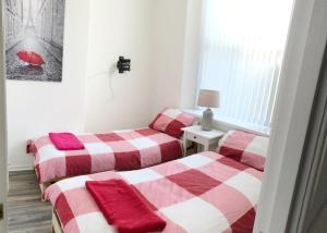 - 2 lits dans une chambre avec des couvertures rouges et blanches dans l'établissement 3 Fitzhamon Embankment APARTMENTS opposite Principality Stadium - free parking nearby - LONG STAY OFFER - newly redecorated March 2024, à Cardiff