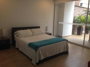 ein Schlafzimmer mit einem Bett und einem großen Fenster in der Unterkunft Moderatto Suites in Medellín