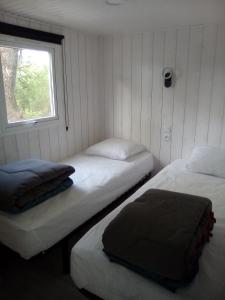 dwa łóżka w pokoju z oknem w obiekcie Camping Les Peupliers w mieście Saint-Père-en-Retz