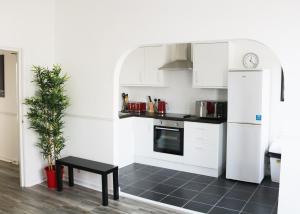 una cucina con armadi bianchi, tavolo e pianta di 3 Fitzhamon Embankment APARTMENTS opposite Principality Stadium - LONG STAY OFFER a Cardiff