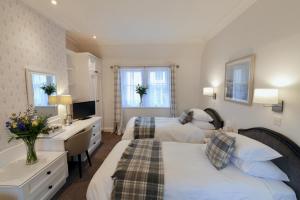 a bedroom with two beds and a desk and a sink at Selkirk Arms Hotel in Kirkcudbright