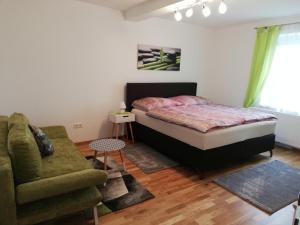 um quarto com uma cama, um sofá e uma cadeira em Ferienwohnung Deisenberger em Furth