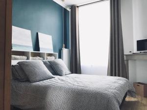 Schlafzimmer mit einem Bett mit blauen Wänden und einem Fenster in der Unterkunft Le Central Wimereux in Wimereux