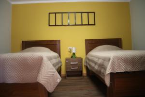 a bedroom with two beds and a table with a lamp at Los Faroles Hostal in Potosí