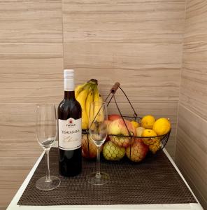 a basket of fruit with a bottle of wine and two glasses at Guesthouse Orlović in Budva