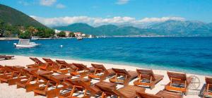 a row of chairs on a beach next to the water at J&B LUX Apartment in Herceg-Novi