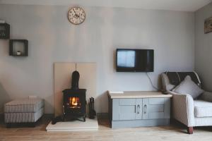 uma sala de estar com lareira e uma televisão na parede em Dolmen Cottage em Glencolumbkille