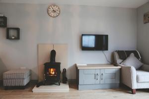 a living room with a fireplace and a tv on the wall at Dolmen Cottage in Glencolumbkille