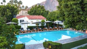 een groot zwembad met stoelen en parasols bij Avalon Hotel & Bungalows Palm Springs, a Member of Design Hotels in Palm Springs