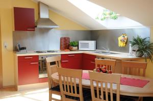 eine Küche mit roten Schränken sowie einem Tisch und Stühlen in der Unterkunft Ferienwohnungen Kramheller in Zwiesel