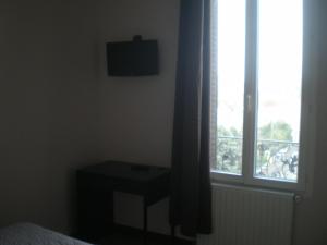 um quarto com uma janela com uma cama e uma mesa em Hôtel Le Bellevue - Paris Porte d'Orléans em Cachan