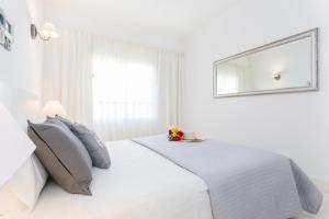 una camera bianca con letto bianco e specchio di Litoral Mar Dream 17, beach front, free Wi-fi, private parking, pool a Portimão