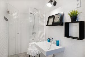 a white bathroom with a sink and a shower at Karma Boutique Apartments in Budapest